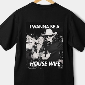 May include: Black t-shirt with a white graphic print of two men. The text on the graphic reads "I wanna be a house wife".