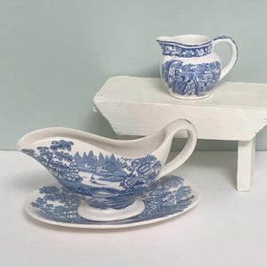 Op de afbeelding: Een witte keramische mok met een zwart handvat en de tekst "But First, Coffee" in een handschriftstijl. De mok staat op een wit oppervlak. De mok is ongeveer 10 cm hoog.