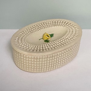 May include: A white ceramic mug with a black handle and the text "But First, Coffee" in a black, bold font. The mug is on a wooden surface. The mug is approximately 10 cm tall.