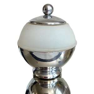 May include: A spherical container featuring a polished chrome base and a matching chrome lid topped with a small ball finial. The center section consists of a translucent white frosted glass band that contrasts with the reflective metallic finish.