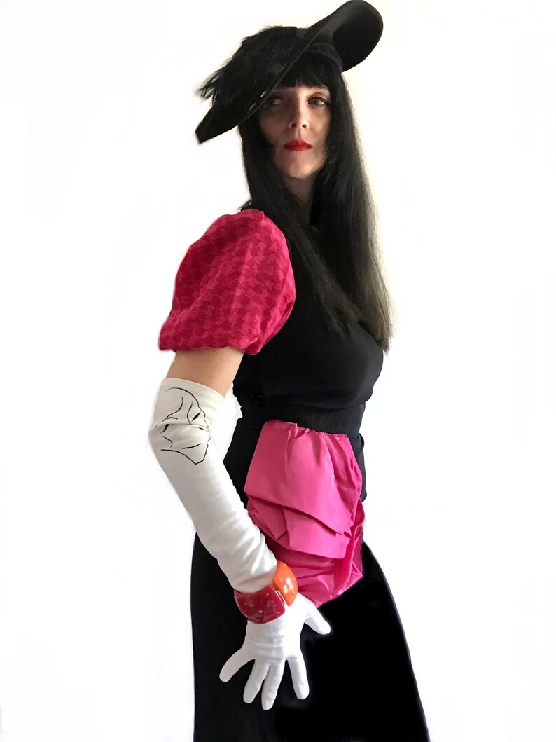May include: A woman wearing a black dress with a pink ruffled skirt, a black hat with a feather, and white gloves. She is wearing a pink and white patterned blouse with puffed sleeves.