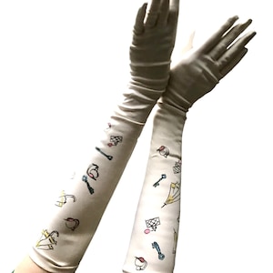 May include: A pair of long, white satin gloves with a whimsical pattern of keys, umbrellas, and other small objects in yellow, blue, pink, and red.
