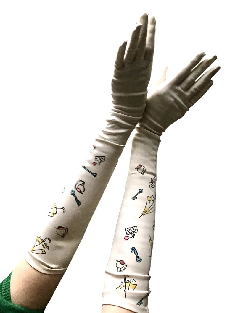 May include: A pair of long, white satin gloves with a whimsical pattern of keys, umbrellas, and other small objects in yellow, blue, pink, and red.