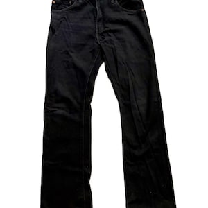 May include: A pair of black denim jeans featuring a classic five-pocket design, a button fly closure, and copper-toned metal rivets at the pocket corners. The jeans have a straight-leg cut with visible stitching along the seams and a waistband.