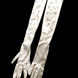 May include: A pair of long white gloves with a pattern of umbrellas, keys, and rings. The gloves are made of a soft, stretchy fabric and have a delicate, feminine look.