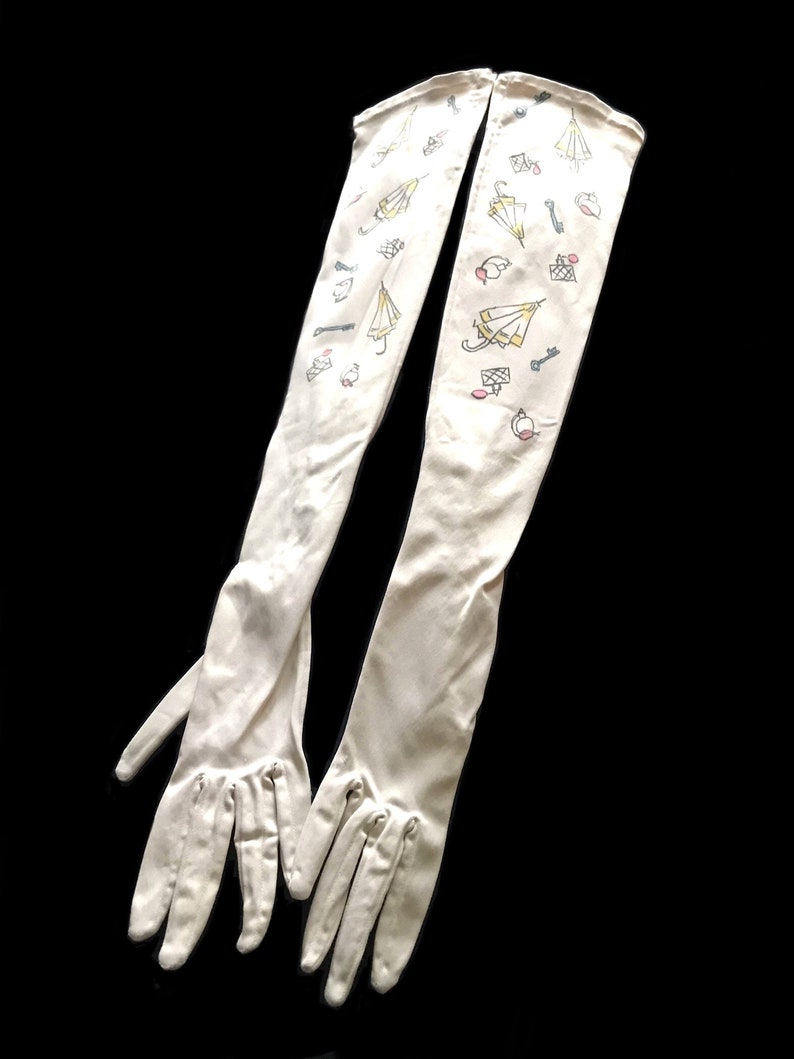 May include: A pair of long white gloves with a pattern of umbrellas, keys, and rings. The gloves are made of a soft, stretchy fabric and have a delicate, feminine look.