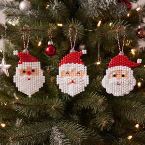 May include: Three Santa Claus ornaments crafted from small white and red beads. Each ornament features a red hat, a white beard, and a face with black eyes and a red nose or mouth, suspended by a red and white twisted string loop.