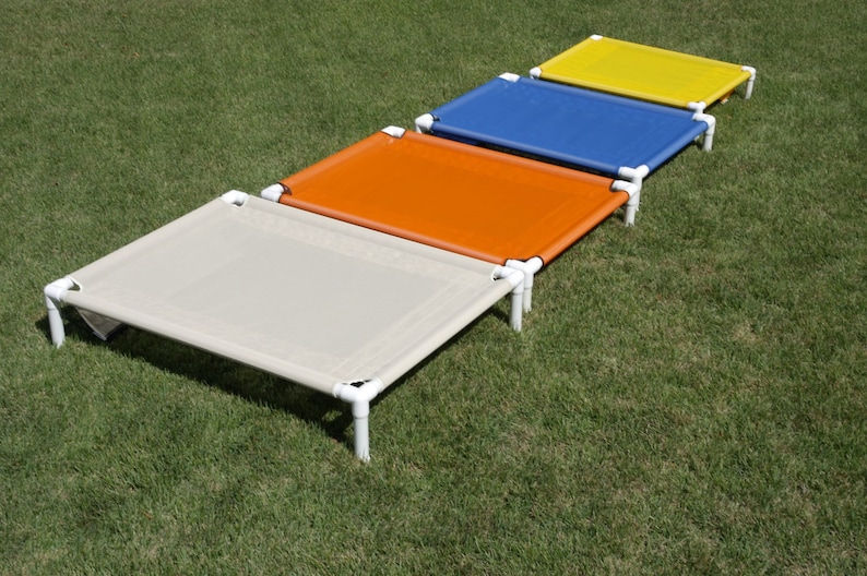 May include: Four elevated pet beds in different colors: beige, orange, blue, and yellow. The beds are made of a sturdy metal frame and a breathable fabric.