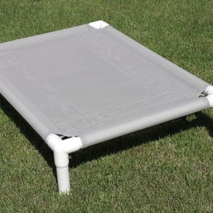 May include: A gray elevated dog bed with a fabric top and white plastic legs.
