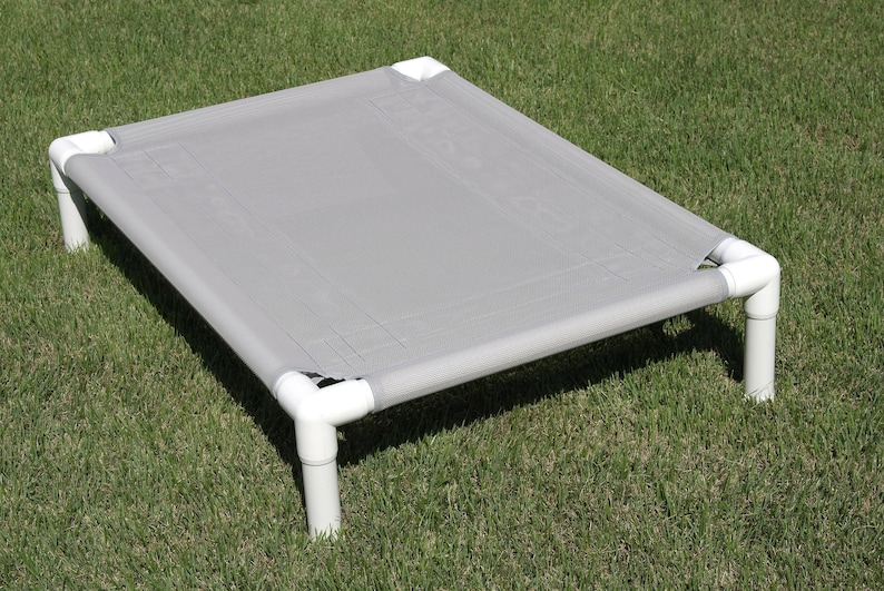 May include: A gray elevated dog bed with a fabric top and white plastic legs.