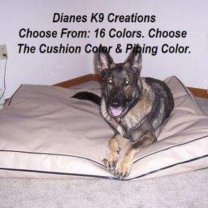 May include: A German Shepherd dog lying on a beige dog bed with black piping. The bed is on a light grey carpet. The text "Dianes K9 Creations Choose From: 16 Colors. Choose The Cushion Color & Piping Color." is visible above the dog.