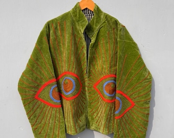 May include: A green velvet jacket with embroidered eye designs. The jacket features a mandarin collar and a striped lining. The eye designs are outlined in red with blue and brown details, creating a striking visual contrast.