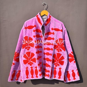 Könnte beinhalten: Eine hellviolette Jacke mit roter Blumenstickerei. Die Jacke hat einen hohen Kragen und einen Reißverschluss. Der Text "NAIRAHANDICRAFT" ist auf der Vorderseite der Jacke zu sehen.