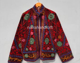 May include: A brown velvet jacket with intricate floral embroidery in shades of red, green, blue, and pink. The jacket features a mandarin collar and is embellished with the text "nairahandicrft".
