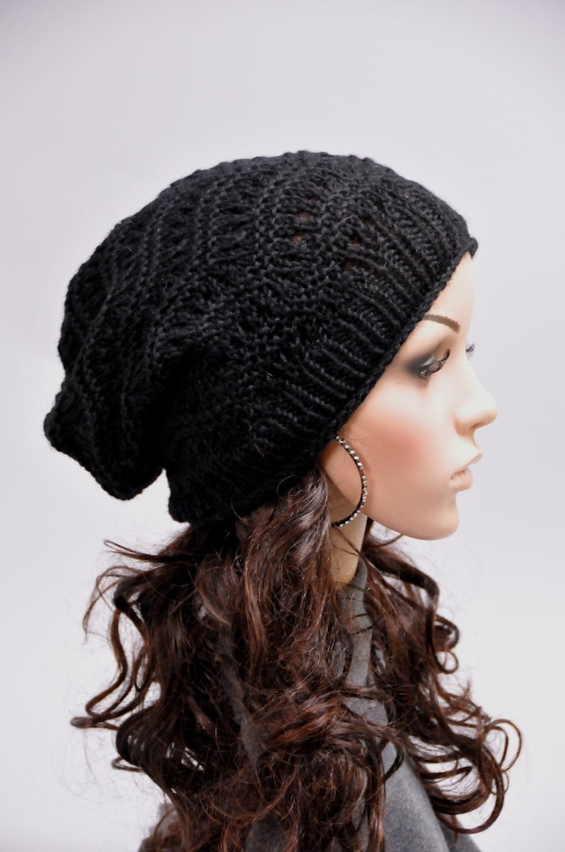 May include: A black knitted beanie with a slouchy fit. The beanie is made of a soft, comfortable yarn and has a simple, stylish design.
