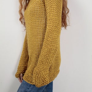 May include: A mustard yellow knitted sweater with long sleeves and a loose fit.