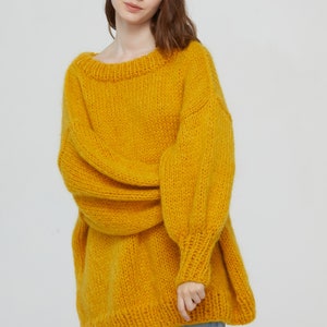 K&ouml;nnte beinhalten: Ein locker sitzender, &uuml;bergro&szlig;er gelber Strickpullover mit langen &Auml;rmeln und einem runden Ausschnitt.
