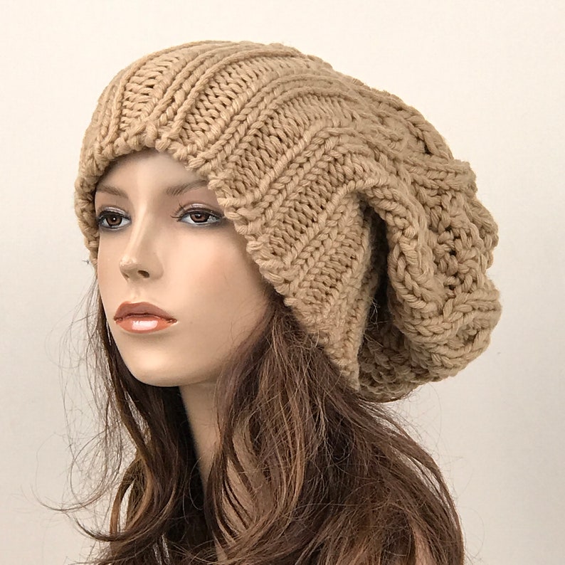 May include: A brown slouchy beanie hat with a cable knit pattern. The hat is made of soft yarn and has a relaxed fit.