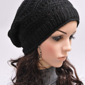 May include: A black knit beanie with a slouchy fit. The beanie is made of a soft, comfortable material and has a simple, stylish design.