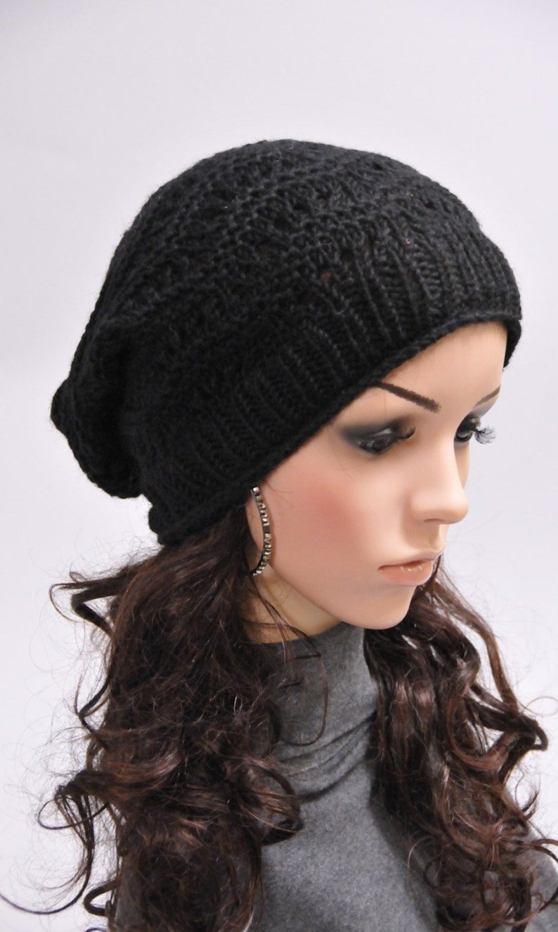 May include: A black knit beanie with a slouchy fit. The beanie is made of a soft, comfortable material and has a simple, stylish design.