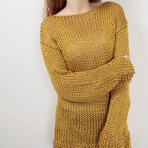 May include: A loose-fitting, mustard yellow knitted sweater with a wide neckline and long sleeves.