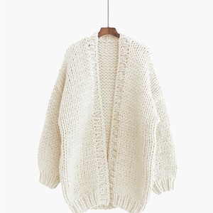 K&ouml;nnte beinhalten: Ein cremefarbener Strickcardigan mit langem, offenem Vorderteil und langen &Auml;rmeln.