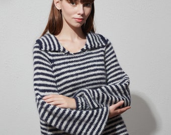 May include: A striped sweater with a wide collar in navy blue and white. The sweater is made of a soft, fuzzy material and has a relaxed fit.