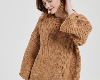 May include: A brown knitted sweater with a relaxed fit and long sleeves. The sweater has a round neckline and a slightly cropped length.