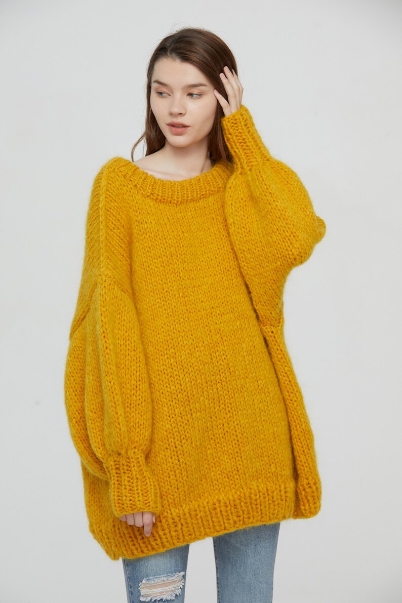 K&ouml;nnte beinhalten: Ein &uuml;bergro&szlig;er gelber Strickpullover mit Rundhalsausschnitt und langen &Auml;rmeln.
