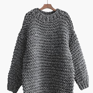 May include: A black and silver chunky knit sweater with a round neckline.