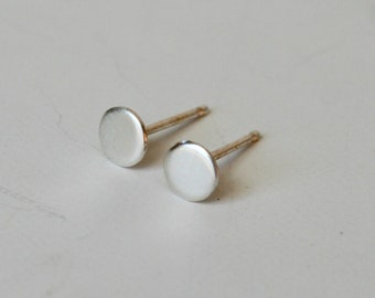 May include: A pair of silver stud earrings with round, flat fronts.