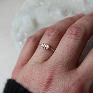 May include: A delicate silver ring with a rose gold three-dimensional elephant design.