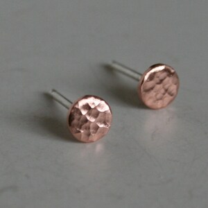 May include: A pair of small, hammered copper stud earrings with silver posts.