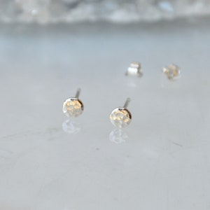 May include: A pair of silver hammered disc stud earrings. The earrings are small and delicate, with a hammered texture that gives them a unique look.