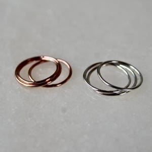 May include: Two sets of three thin, stacked rings. One set is rose gold and the other is silver.