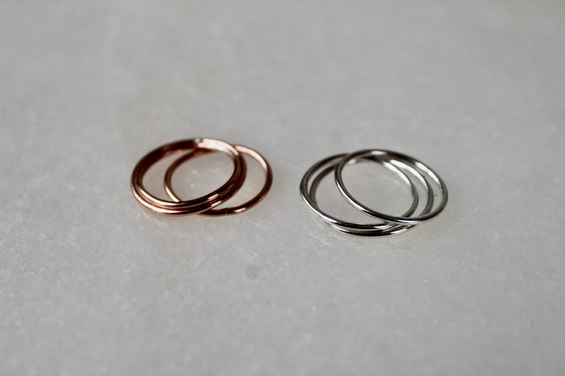 May include: Two sets of three thin, stacked rings. One set is rose gold and the other is silver.