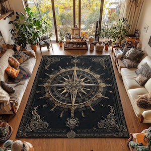 May include: A rectangular area rug featuring a large, central gold compass rose design on a black background. The rug is decorated with intricate, ornate filigree patterns in the corners and along the borders, creating a detailed, symmetrical aesthetic.