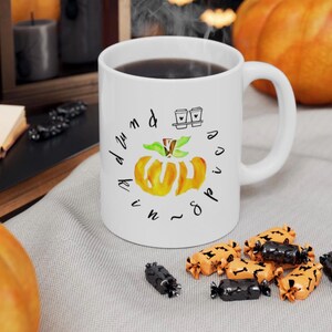 Op de afbeelding: Witte keramische mok met een zwart-witte illustratie van een pompoen en de tekst "pumpkin spice and everything nice".