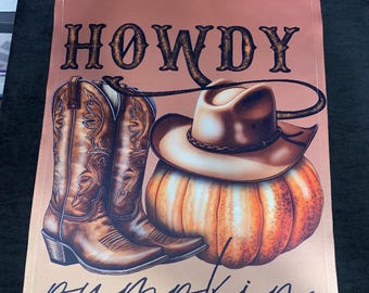 May include: A rectangular garden flag with a light brown background featuring the text HOWDY in dark brown block letters at the top and pumpkin in black script at the bottom. The design includes brown cowboy boots and a brown cowboy hat on a pumpkin.