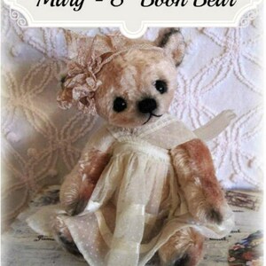 Può includere: Un orsacchiotto Booh di 8 pollici fatto a mano di nome Mary, che indossa un vestito bianco con bordino in pizzo e un cerchietto di fiori rosa. L'orso è seduto su una superficie di legno con uno sfondo bianco.