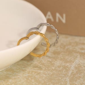 May include: Two hoop earrings with a twisted rope texture. One earring is finished in a bright gold tone, while the other is finished in a polished silver tone. Both earrings feature a circular design with a hinged closure mechanism for secure wear.
