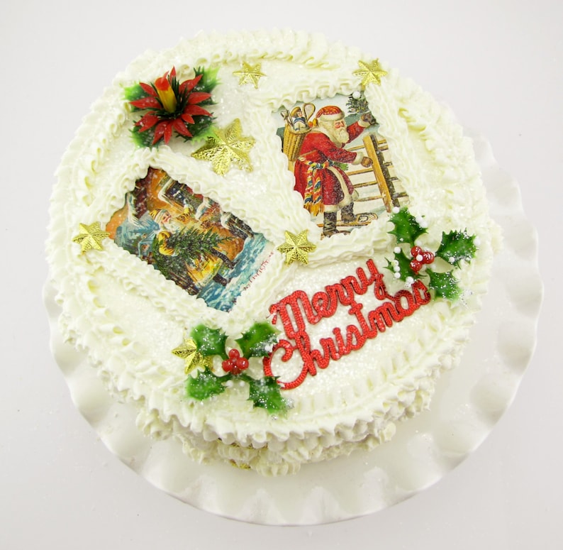 K&ouml;nnte beinhalten: Ein wei&szlig;er Kuchen, verziert mit wei&szlig;em Frosting, rotem Stechpalmenlaub, goldenen Sternen und Vintage-Weihnachtsbildern. Der Kuchen ist mit den Worten "Frohe Weihnachten" beschriftet.