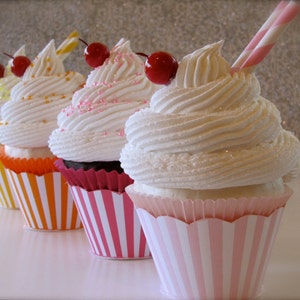May include: Five cupcakes with white frosting and red cherries on top. The cupcakes are in striped paper liners. The liners are pink and white, orange and white, and green and white.