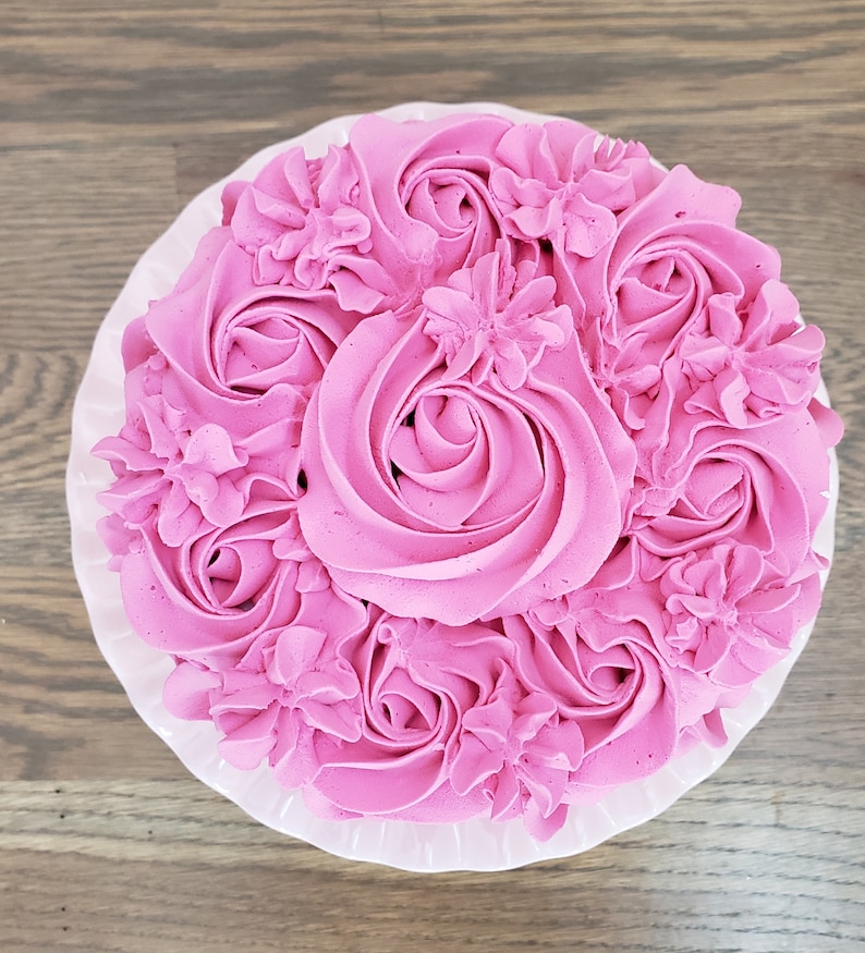 Puede incluir: Un pastel rosa decorado con glaseado rosa en forma de rosas y flores.