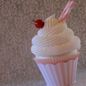 May include: A pink and white striped cupcake with white frosting and a red cherry on top. A pink and white striped straw is sticking out of the frosting.