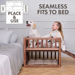 May include: A wooden dog bed with a ramp, featuring a light-colored dog and a young girl. The bed has two levels with a cushion on each level. The text "SEAMLESS FITS TO BED" is displayed.