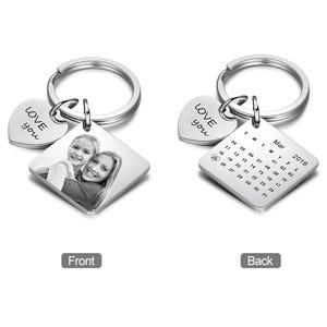 May include: Silver keychain with a square photo frame, a heart charm with the words "LOVE you" engraved, and a square calendar charm with the month of March 2019 engraved.