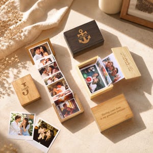 Può includere: Tre scatole rettangolari in legno con coperchio, una marrone scuro con un'ancora e il nome Janet, una in legno chiaro con la lettera J e Janet, e una in legno chiaro con il testo Having your love is my greatest fortune. Una striscia fotografica.