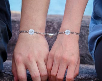 May include: Two silver bracelets with heart charms and round pendants engraved with the letters "M" and "B".