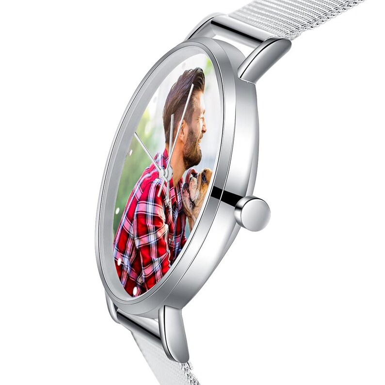 May include: Silver wristwatch with a mesh band. The watch face displays a color photo of a person in a red plaid shirt with a dog. The watch has a silver case and a white band.